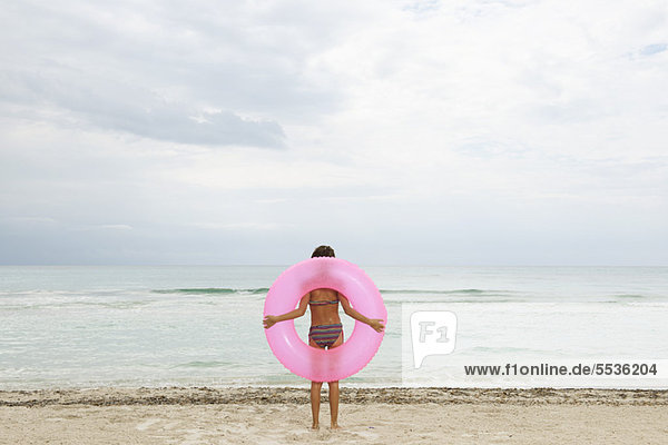 Mädchen mit aufblasbarem Ring am Strand  Rückansicht
