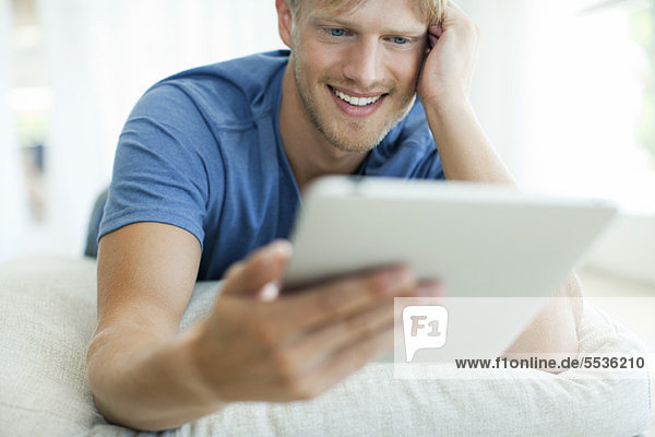 Auf dem Bauch liegender Mann beim Betrachten des digitalen Tabletts