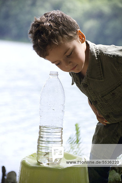 Junge schaut auf Fisch in der Wasserflasche