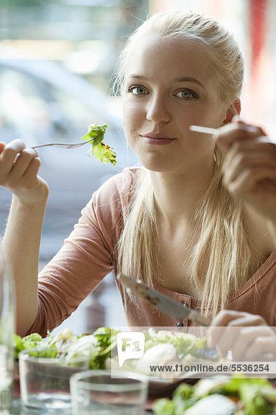 Young blond woman eating salad