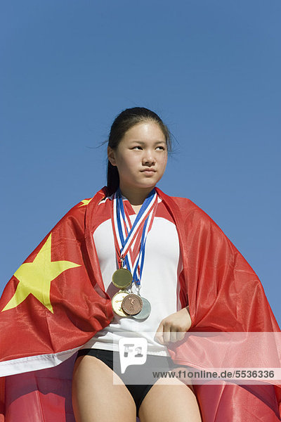 Athletin auf dem Siegerpodest  in chinesische Flagge gehüllt