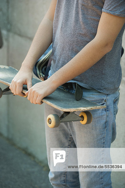 Man holding skateboard  mid section