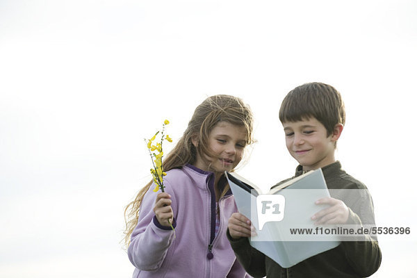 Kinder beim gemeinsamen Lesen im Freien