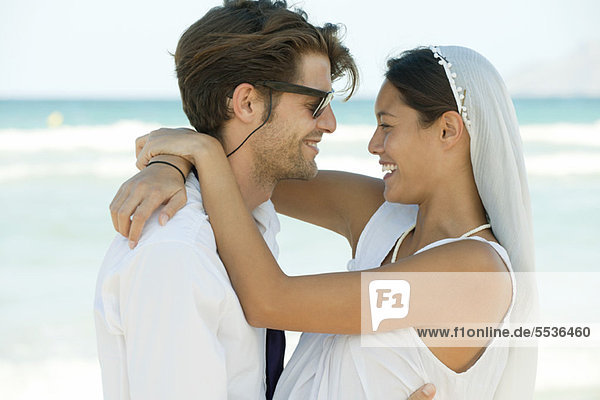 Braut und Bräutigam umarmend am Strand