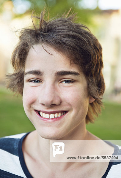Close-up of teenage boy smiling outdoors