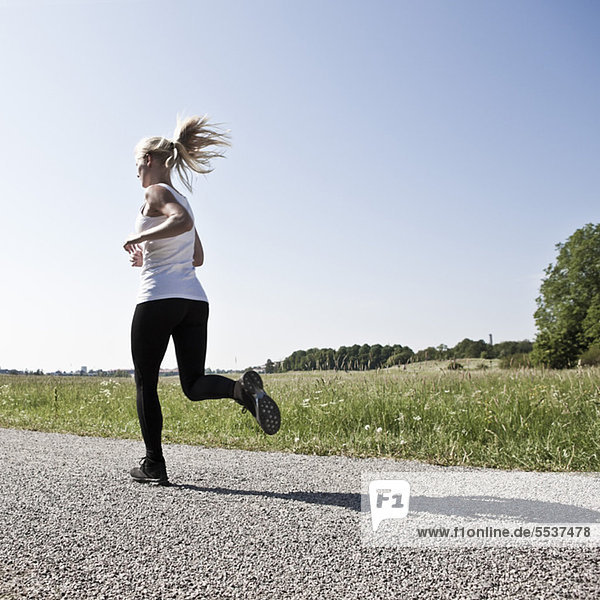 Volle Länge der jungen Frau beim Joggen auf der Straße