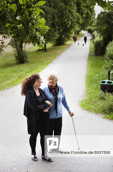 Mittlere erwachsene Frau mit ihrer Großmutter beim Spaziergang im Park
