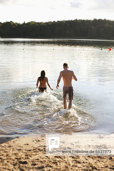 Rear view of couple running in water