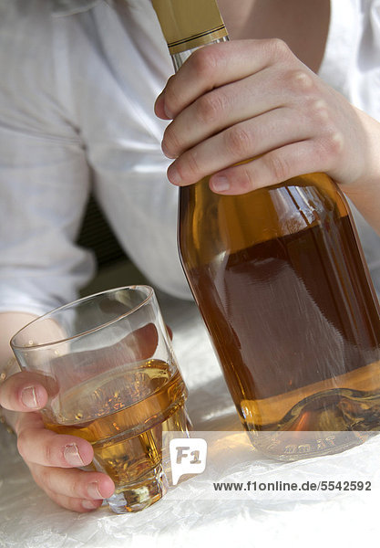 Frauenhände halten eine Flasche und ein Glas mit hochprozentigem Alkohol  weiblicher Alkoholismus