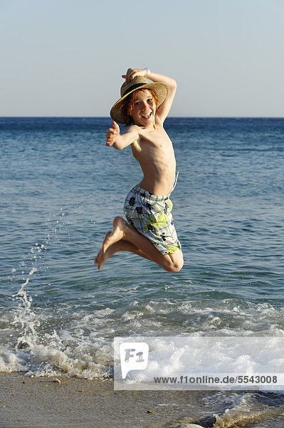 Junge hüpft vor Freude am Strand am Meer