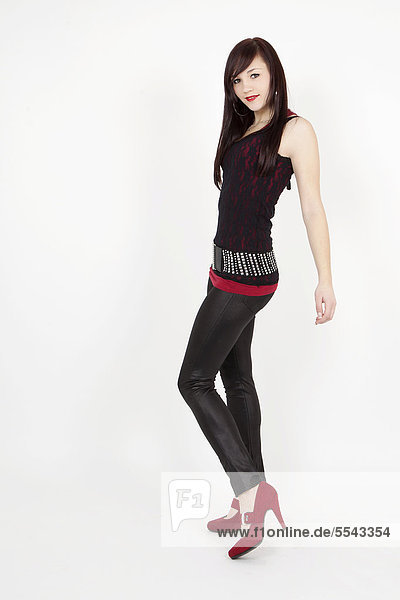 Junge Frau mit schwarzem Top  Lack-Leggins und roten High-Heels