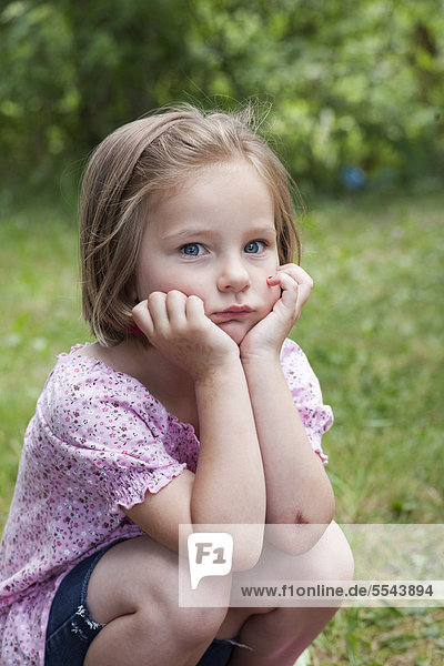 Girl  4  in a squatting position with a pensive look