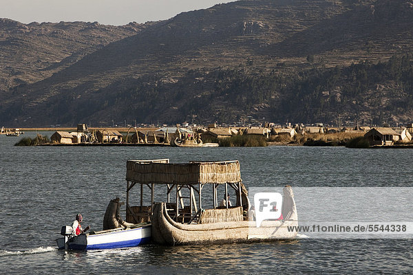 Traditionelles Schilfboot wird von einem motorisierten Boot angeschoben  auf dem Titicacasee schwimmende Inseln der Urus  aus dem dort wachsenden Totora-Schilf gefertigt  Puno  Peru  Südamerika