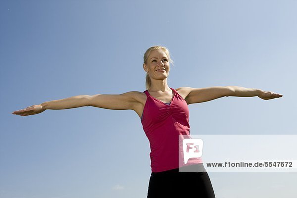 Young woman outdoors with outstretched arms