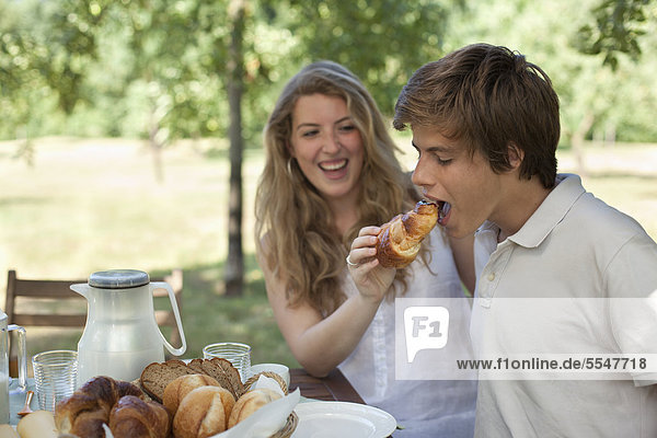 Junge Frau füttert ihren Freund mit einem Croissant