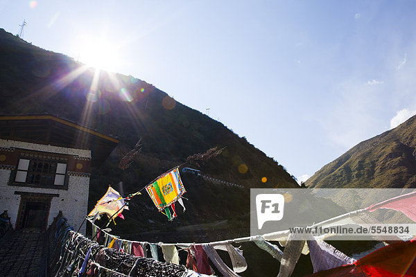 Haus mit Brücke und Gebetsfahnen  Bhutan