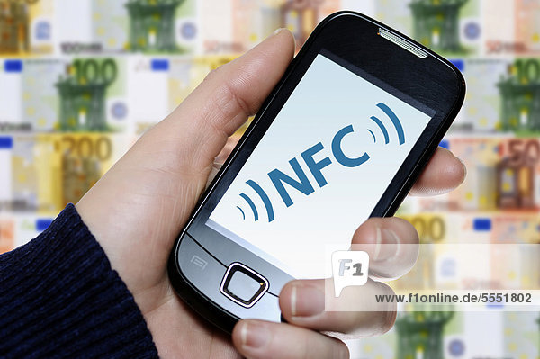 Hand holding a smartphone displaying NFC  Near Field Communication