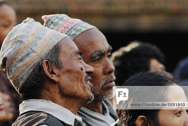 Men with traditional headwear watching procession  Taumadhi square  Bhaktapur  Kathmandu Valley  Nepal  Asia