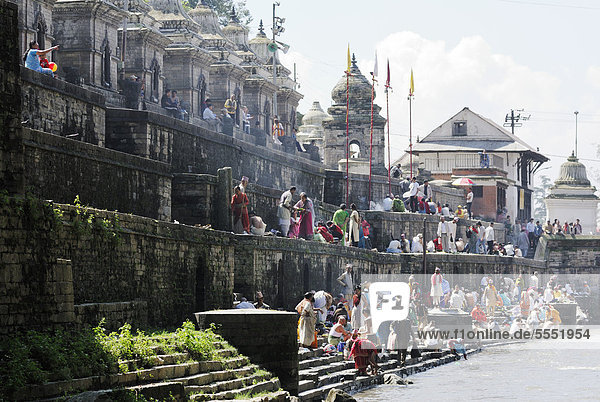 Pilger auf Stufen des Pandra Shivalaya Komplexes gegenüber den Ghats von Pashupatinath am heiligen Bagmati Fluss  Kathmandu  Nepal  Asien