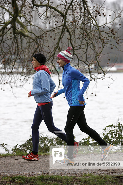 Two young women jogging in winter  wearing wind and waterproof performance apparel