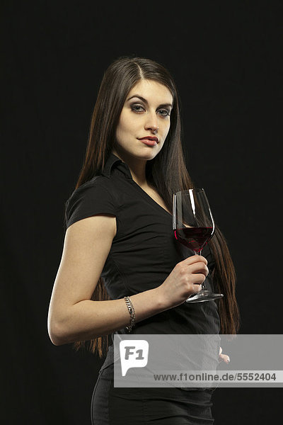 Young woman in evening dress holding a glass of red wine