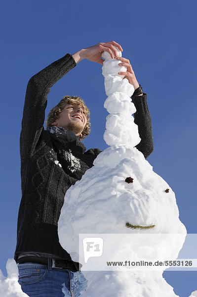 Ein junger Mann baut einen Schneemann  Schwarzwald  Baden-Württemberg  Deutschland  Europa  ÖffentlicherGrund