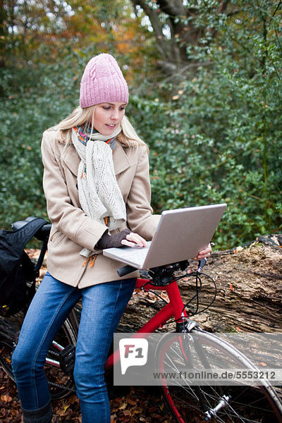 Frau im Freien mit Laptop und Fahrrad