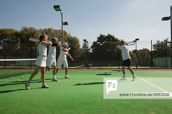 Senior and mature adults practising tennis