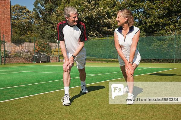 Reife Frau und Alter Mann durchführen von Übungen zum Tennisplatz Aufwärmen