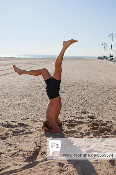 Man performing headstand on a beach