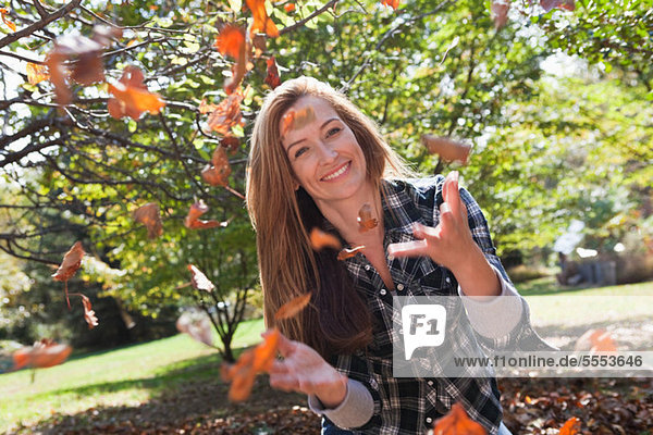 Woman throwing autumn leaves in the air