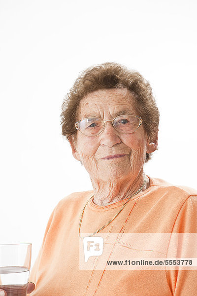 Lächelnde alte Frau mit Brille hält ein Glas Wasser  Portrait