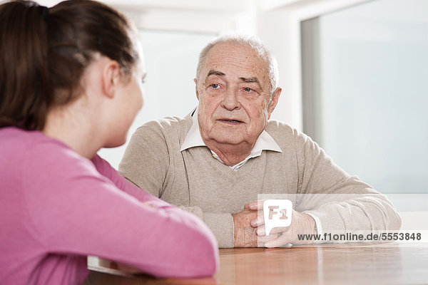 Young woman and senior man sitting at table