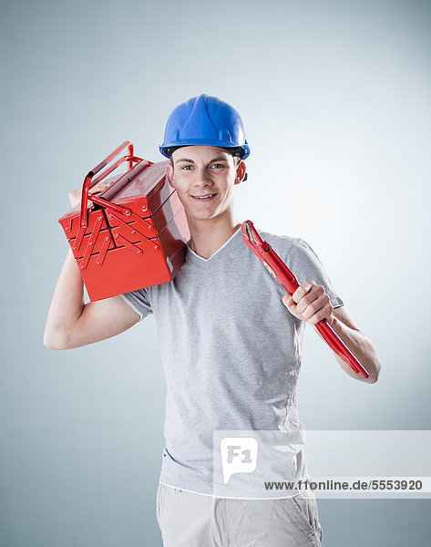 Young man wearing hard hat holding tools  portrait
