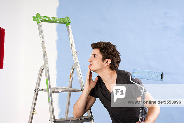 Junger Mann schaut auf eine frisch gestrichene Wand