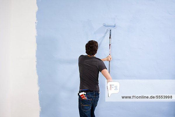 Junger Mann streicht eine Wand