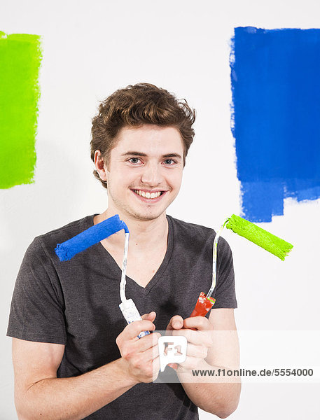 Smiling young man painting a wall