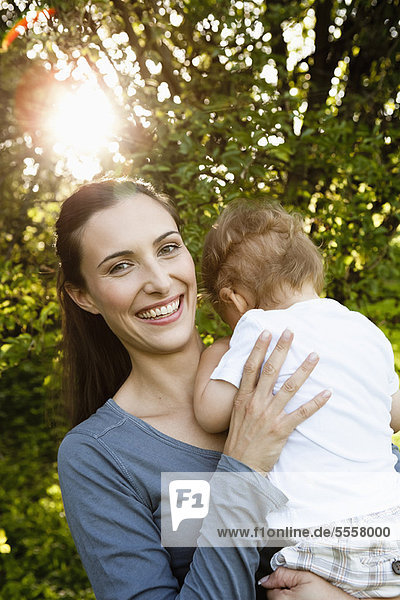 Smiling mother holding toddler outdoors