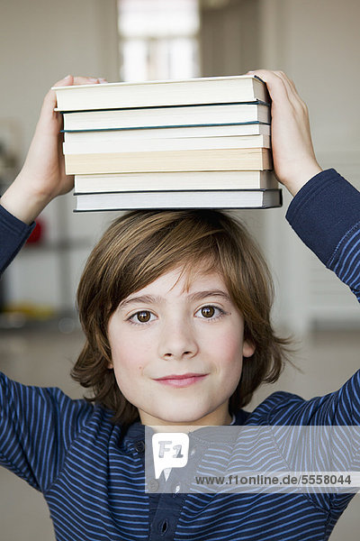 Junge  der Bücher auf dem Kopf balanciert.