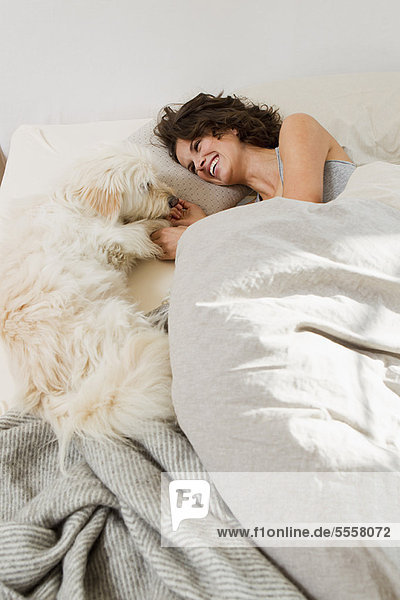 Frau entspannt im Bett mit Hund