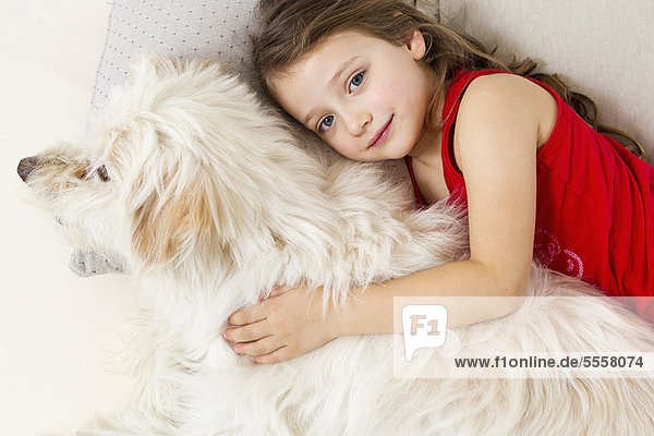 Girl relaxing in bed with dog