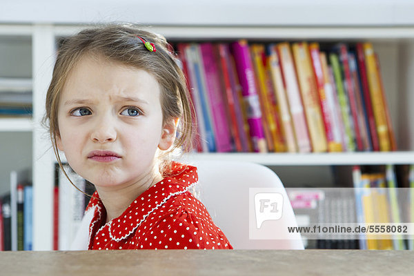 Frowning girl sitting at table