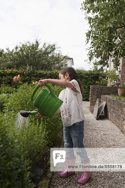 Mädchen gießen Pflanzen im Hinterhof