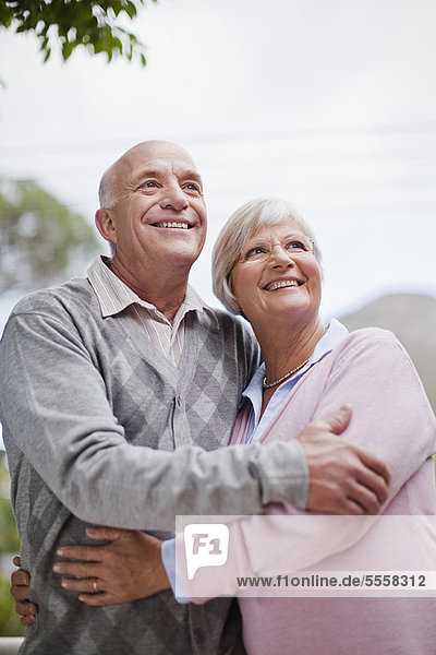 Lächelndes älteres Paar  das sich im Freien umarmt.