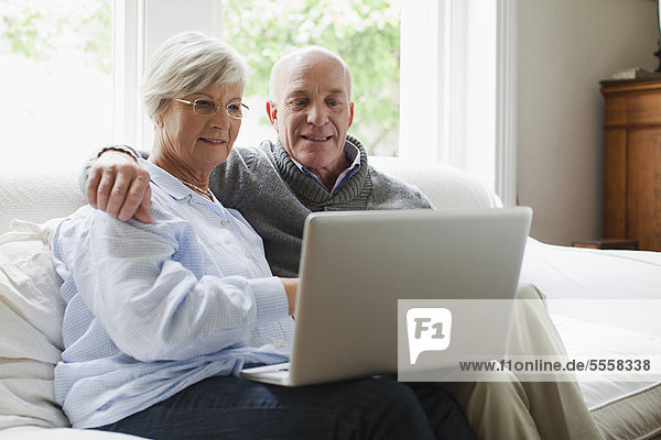 Smiling older couple using laptop