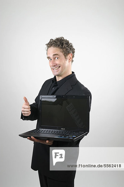 Geschäftsmann in schwarzem Anzug mit Laptop  Daumen hoch