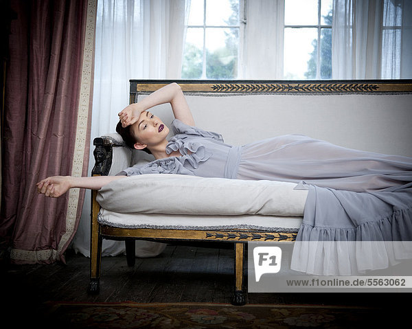 liegend liegen liegt liegendes liegender liegende daliegen Frau Couch lang langes langer lange Kleidung Kleid grau