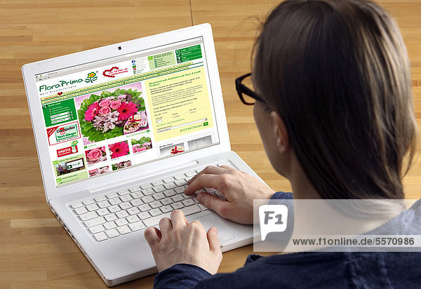 Frau am Laptop surft im Internet  Onlineshop für Blumen