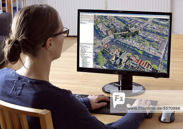 Frau am Computer surft im Internet  Google Earth  3D-Stadtplan  Google Streetview