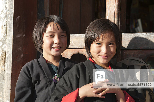 Two smiling girls portrait dressed in traditional costume in the village of Thinleygang near Punakha the Himalayas Kingdom of Bhutan South Asia Asia